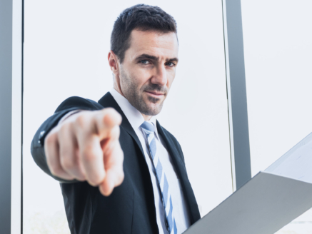 A businessman is pointing the finger to command work with an office worker. The boss is pointing a finger into an employee in the company. The businessman points the finger at you.